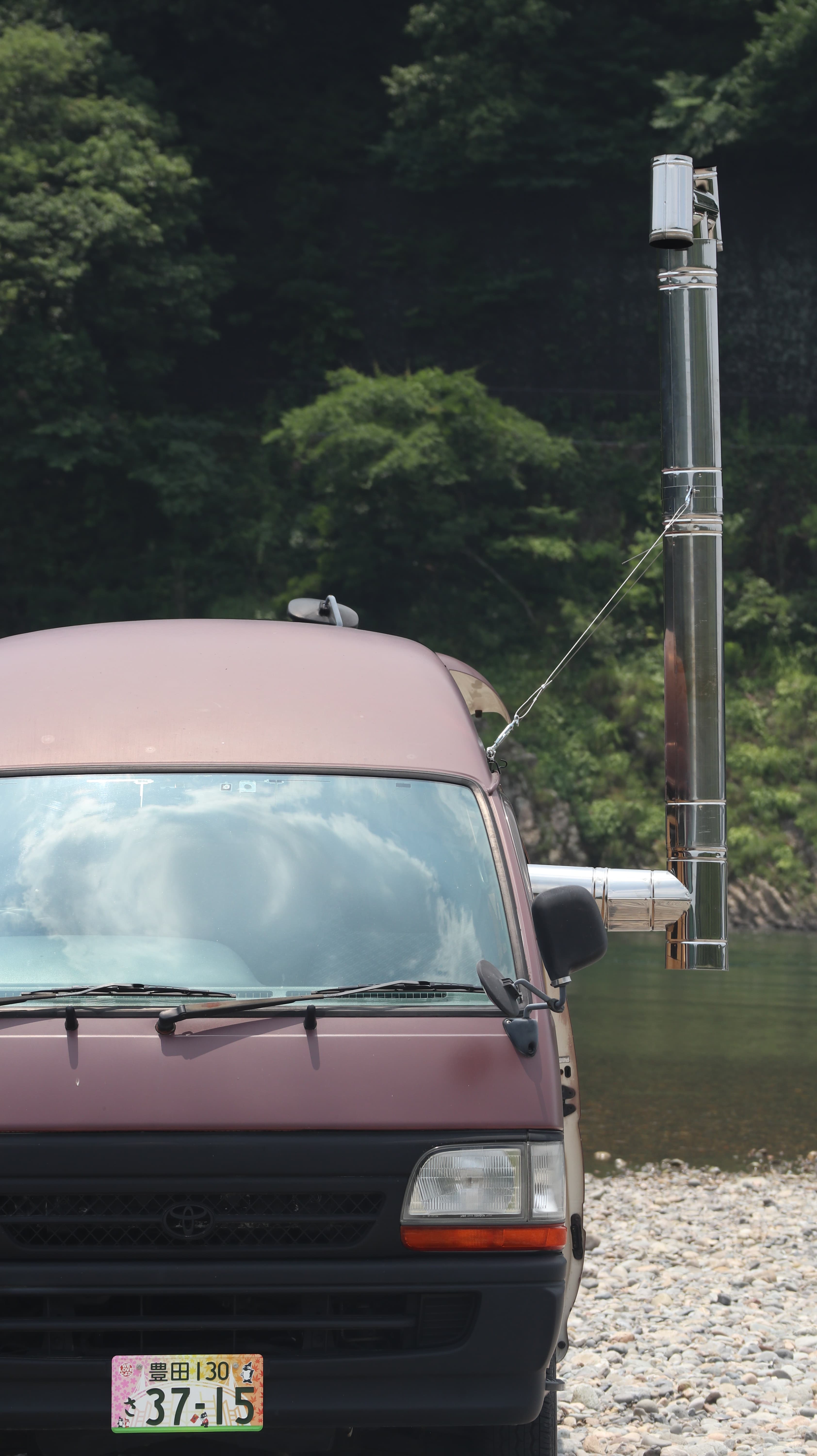 川辺に停まる煙突つきのサウナカー